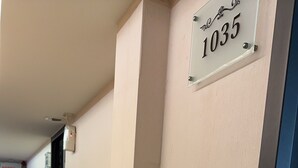 Um corredor com uma placa indicando o quarto 1035. As paredes são simples e o chão possui um tapete estampado.