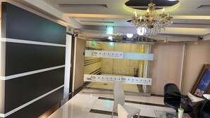 Um hall de hotel moderno com um candelabro, um balcão de recepção e placas de sinalização.