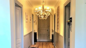 A hallway with wooden flooring, a chandelier, and a door at the end. - Villa Denise (Vals-les-Bains)