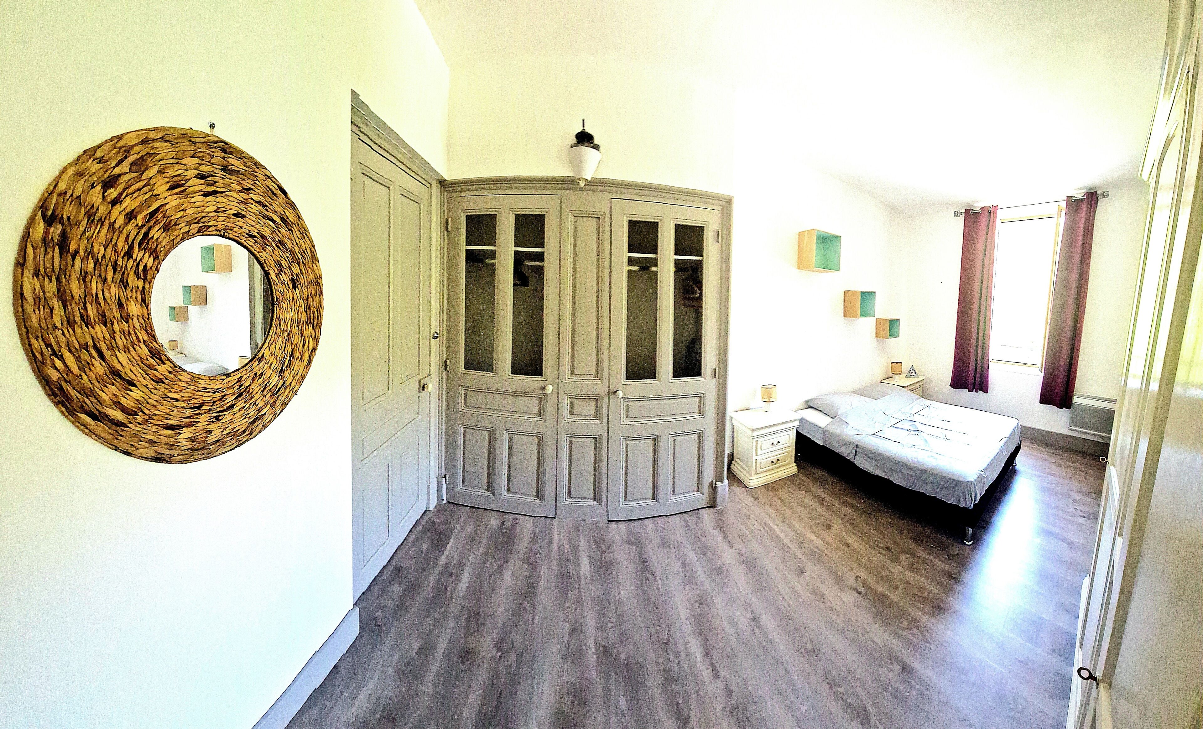 Une chambre avec un lit, une table de chevet, une armoire et un miroir au mur.