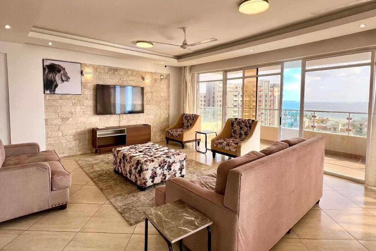 Un salón amplio con pared de piedra, televisor de pantalla plana, sofá, dos sillones y una mesita de centro.