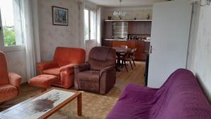A living room with two sofas, a coffee table, and a kitchen in the background. - Quiet, 70s-style house with large garden in the heart of the Lot et Garonne region (Saint-Étienne-de-Fougères)