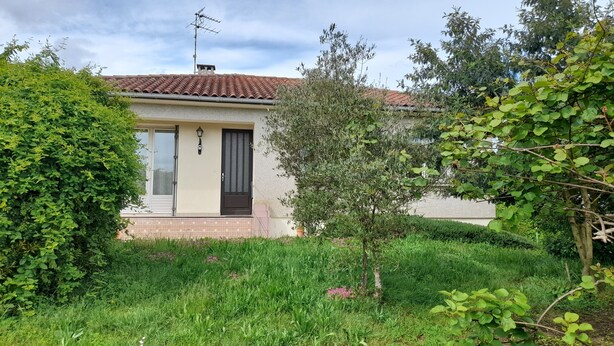 A house with a tiled roof, a small porch, and a garden with various plants and flowers. - Quiet, 70s-style house with large garden in the heart of the Lot et Garonne region (Saint-Étienne-de-Fougères)