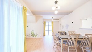 Un comedor con mesa y sillas de madera, una lámpara en el techo y una ventana con cortinas.
