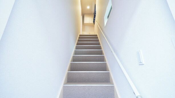Una escalera que lleva a un rellano con una puerta e interruptor de luz en la pared.