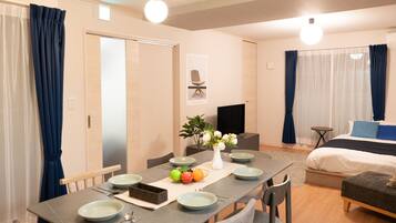 A modern hotel room with a dining area, a bed, and a TV.