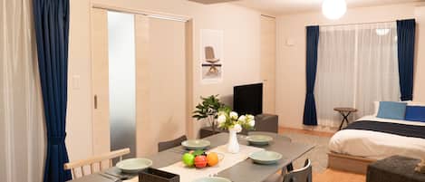 A modern hotel room with a dining area, a bed, and a TV.