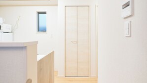 Una habitación moderna y minimalista con un armario de madera, un ventanal pequeño y un microondas sobre una encimera.