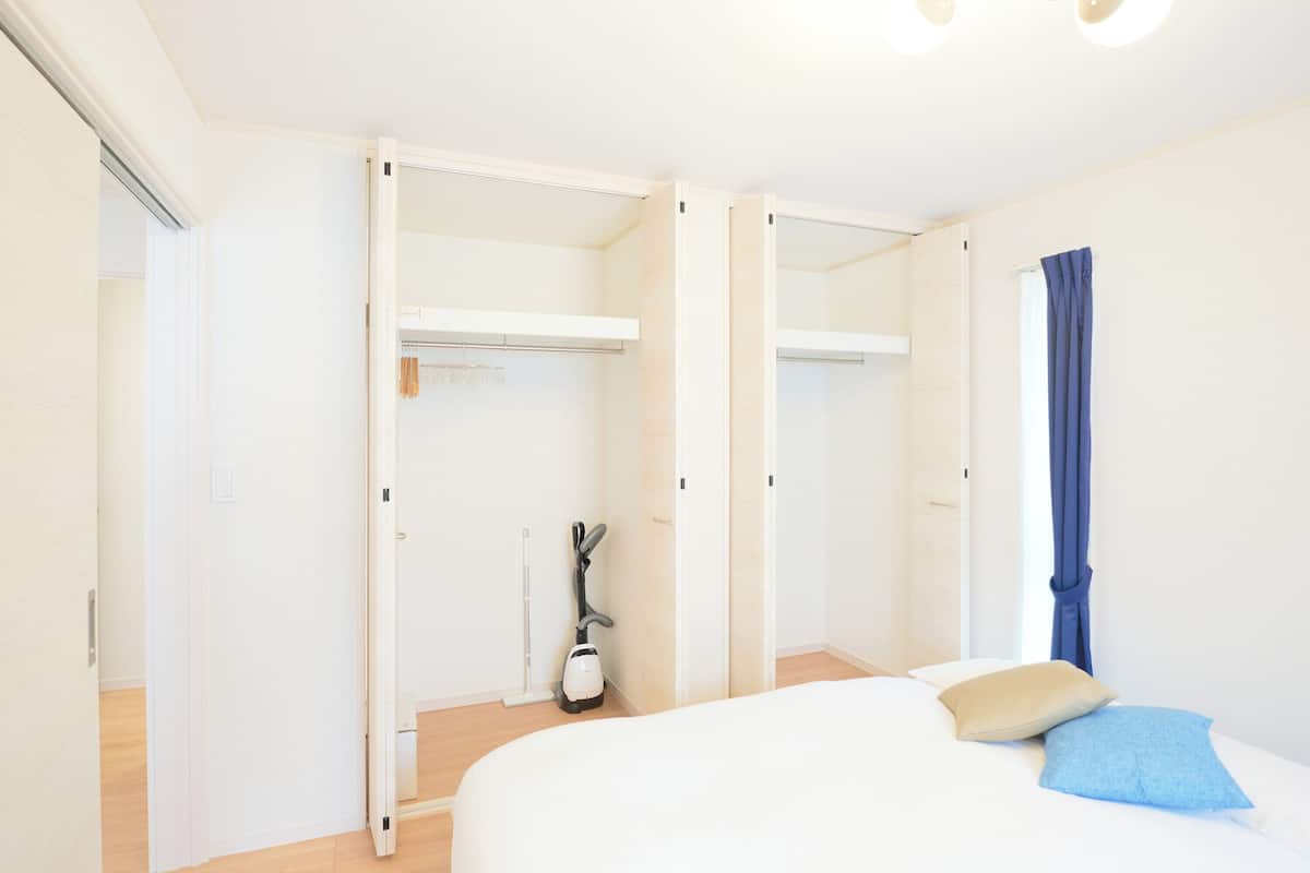 A bedroom with a bed, a closet, and a vacuum cleaner.