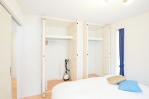 Een slaapkamer met een bed, een kast en een stofzuiger.
