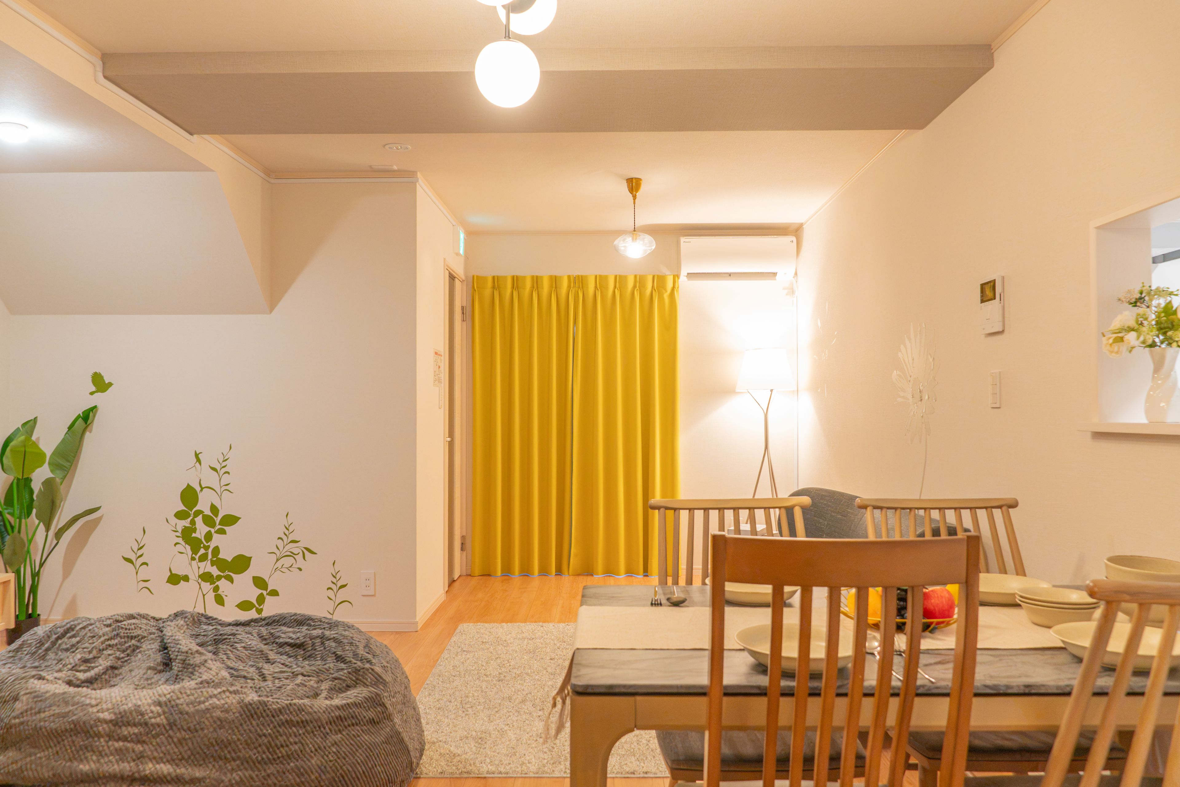A modern living room with a dining area, a yellow curtain, and a plant.