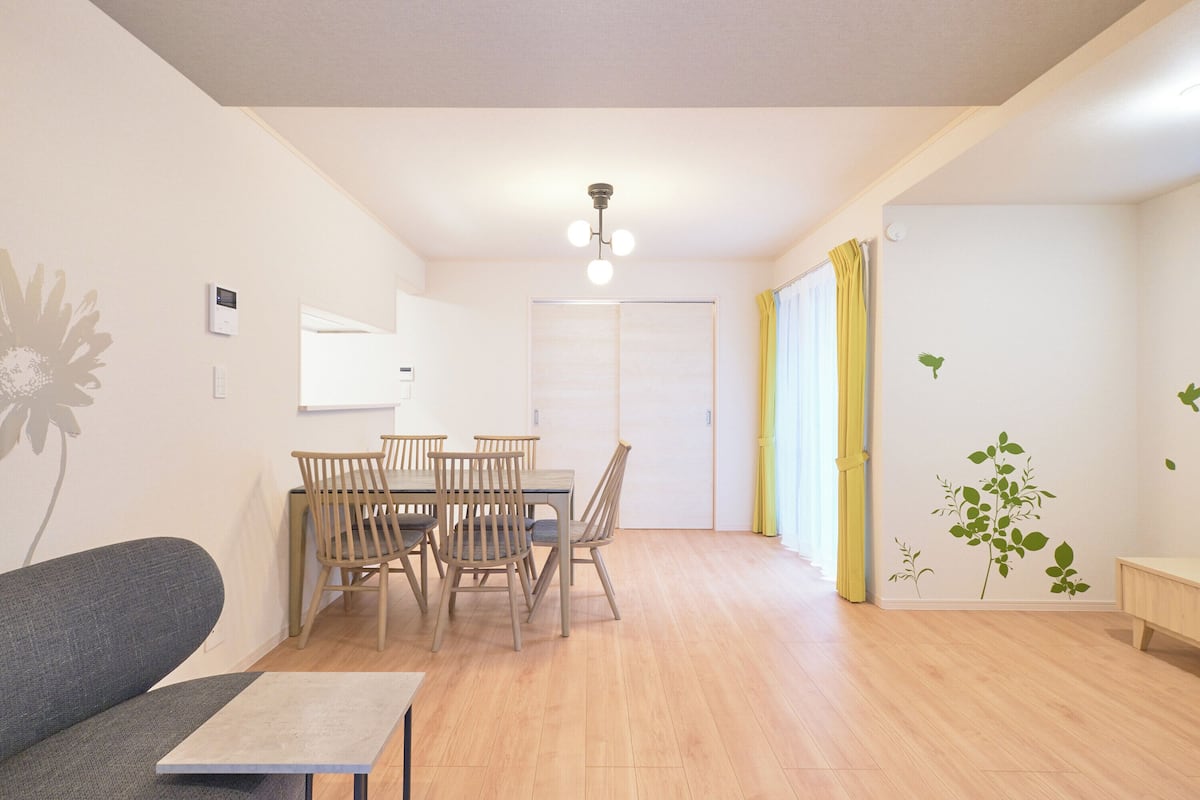 A living room with a sofa, a dining table with chairs, a small table, and a ceiling light.