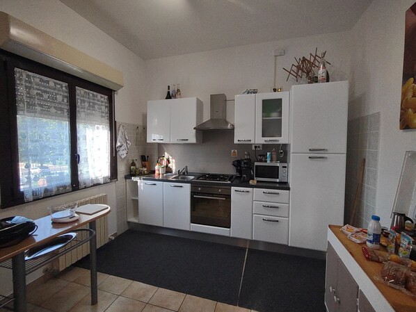 A modern kitchen with white cabinets, a stove, microwave, and a window with a view. - Halfway between Ferrara and Ravenna, a step away from the Comacchio valleys. (Filo)
