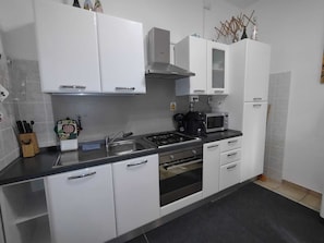 A modern kitchen with white cabinets, a gas stove, a microwave, and a coffee maker. - Halfway between Ferrara and Ravenna, a step away from the Comacchio valleys. (Filo)