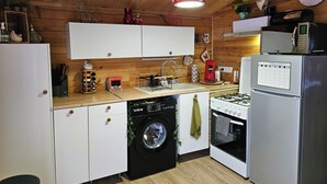 A compact kitchen with white cabinets, a washing machine, a stove, and a refrigerator.