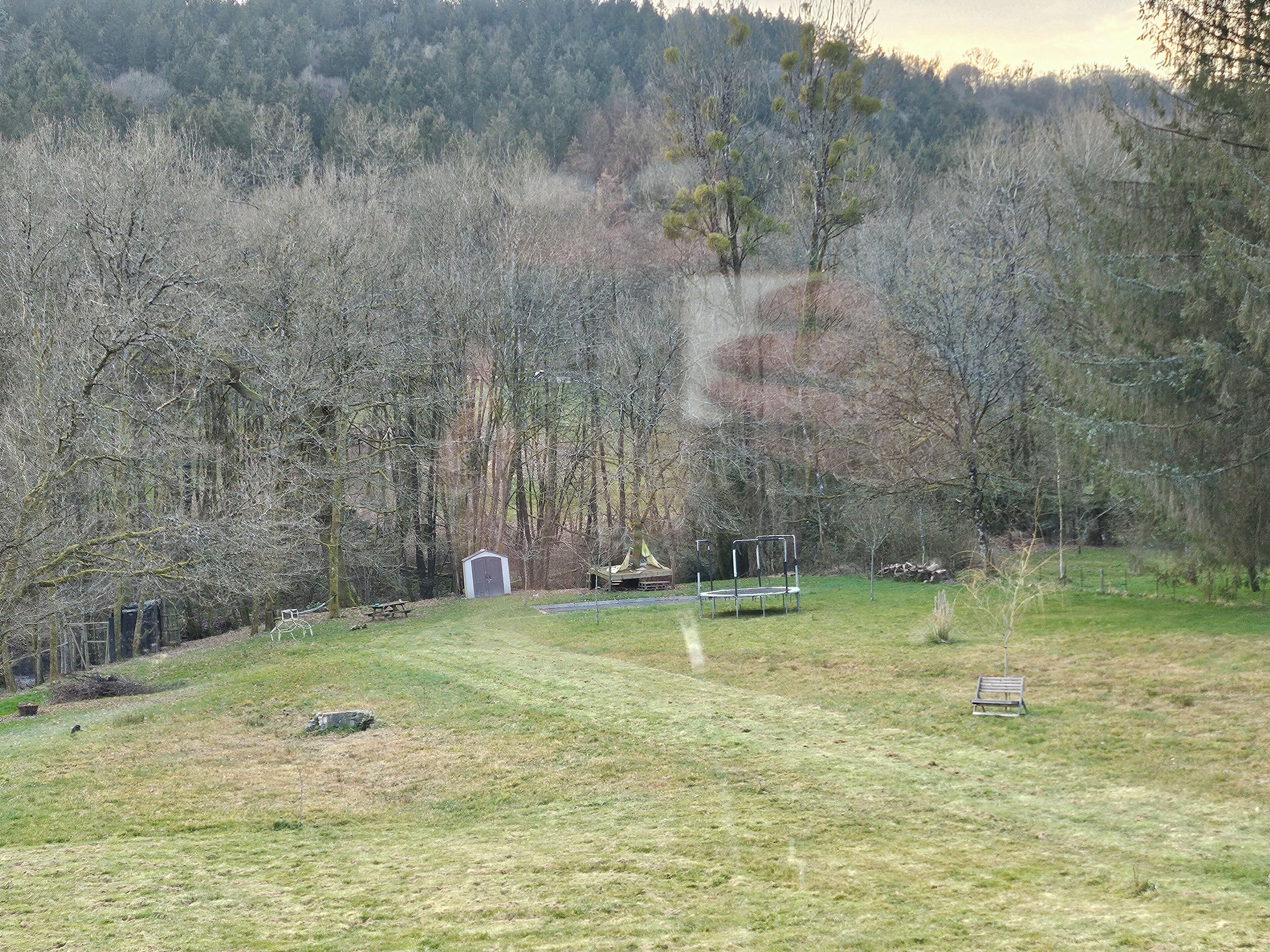 Una zona enjardinada amb un cobert petit, una banca i una taula de picnic.