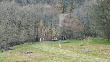 Una zona enjardinada amb un cobert petit, una banca i una taula de picnic.