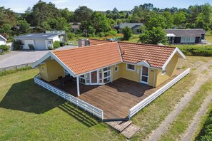 A yellow building with a wooden deck, a garage, and a number 21 sign.