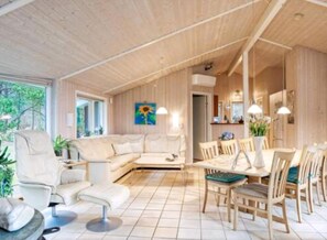 Ein geräumiger Wohnbereich mit Sofa, Esstisch, Stühlen und einem Bild an der Wand.