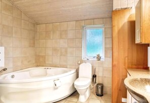 Une salle de bain avec une baignoire, des toilettes et une fenĂȘtre.