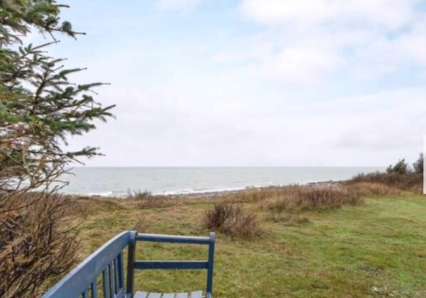 Un banc placĂ© face Ă une Ă©tendue dâherbe, dâoĂč lâon peut admirer la mer.