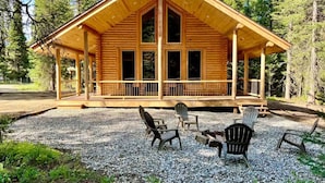 A wooden cabin with a porch, surrounded by gravel and trees. - Wrangler’s Retreat | 7 Mi to YNP | Private Pond (West Yellowstone)