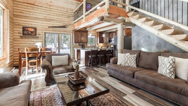A log cabin interior with a living room, dining area, kitchen, and a staircase. - Wrangler’s Retreat | 7 Mi to YNP | Private Pond (West Yellowstone)