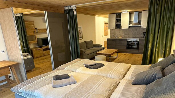 A compact living space with a bed, a sofa, a small table, and a kitchenette. - Apartment in Saalfelden near Ski Slopes (Saalfelden am Steinernen Meer)