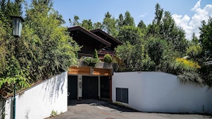 A building with a wooden facade, a garage, and a white wall with a small window. - Alpine Hideaway in Saalfelden (Saalfelden am Steinernen Meer)