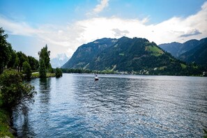 A lake with a sailboat, surrounded by mountains and greenery.