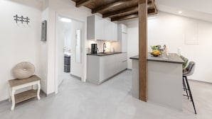 A modern kitchen with a central island, wooden ceiling beams, and a small seating area. - Apartment 'Exklusive "DG"' with Lake View, Balcony and Wi-Fi (Konstanz)