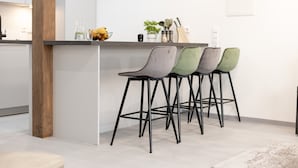 A modern kitchen with a bar area, featuring a wooden column, a white countertop, and four bar stools. - Apartment 'Exklusive "DG"' with Lake View, Balcony and Wi-Fi (Konstanz)
