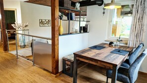 A modern kitchen with a wooden table, bench seating, and a view of the outdoors. - Wald Chalet Maxl – Where Time Stands Still and the Soul Finds Peace (Untergriesbach)