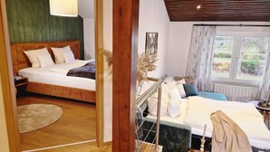 Een slaapkamer met een bed, nachtkastje en een raam met uitzicht op groen.