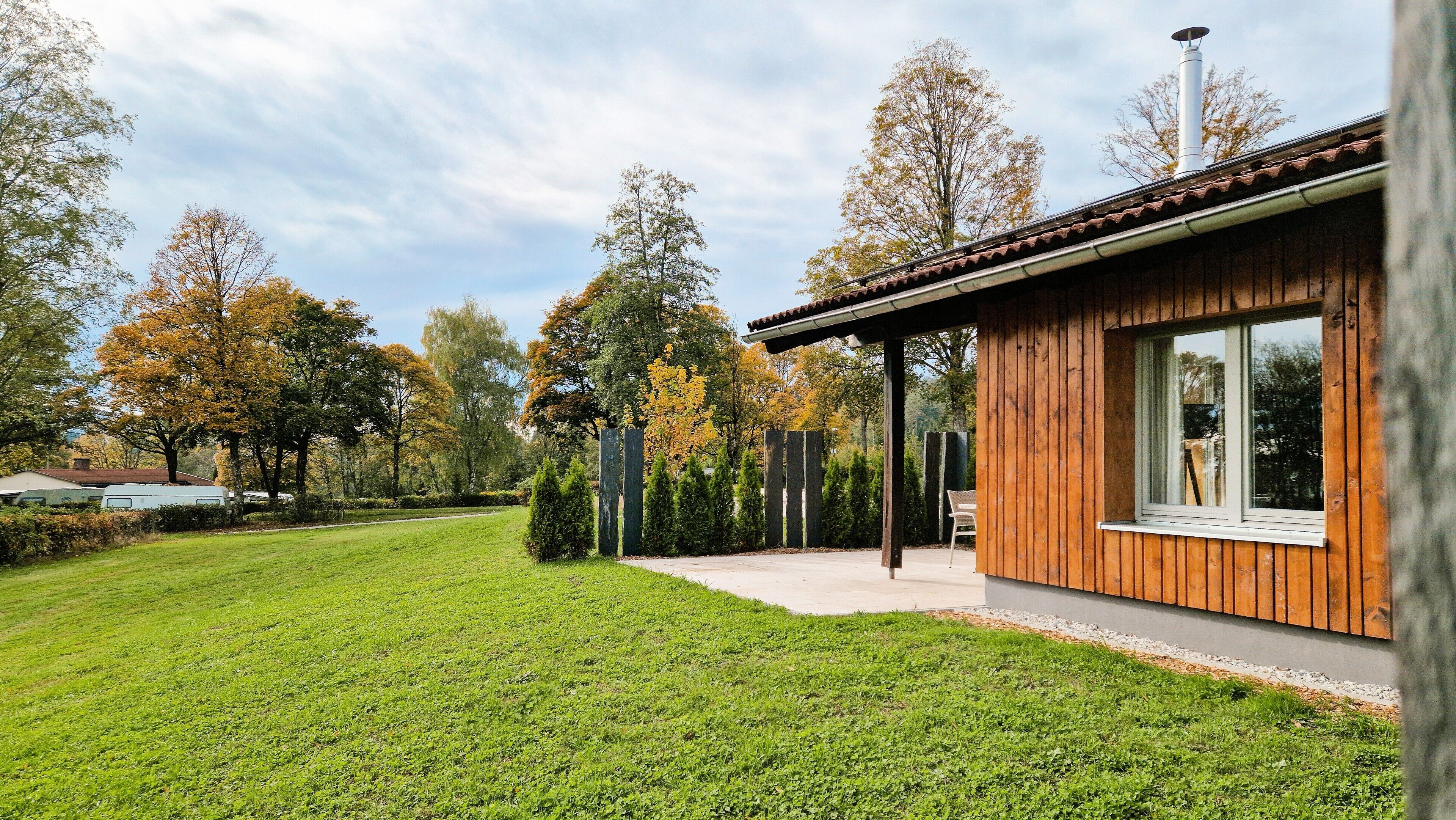 Une maison moderne avec une façade en bois, un porche abrité et une pelouse bien entretenue.