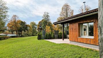 Une maison moderne avec une façade en bois, un porche abrité et une pelouse bien entretenue.