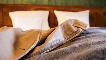 A bed with a brown blanket and pillows.