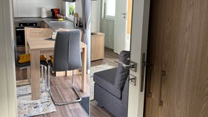 A compact kitchen with modern appliances, a dining area with a table and chairs, and a small seating area with a sofa. - Tiny Home 'Franzl' with Mountain View, Wi-Fi and Air Conditioning (Untergriesbach)