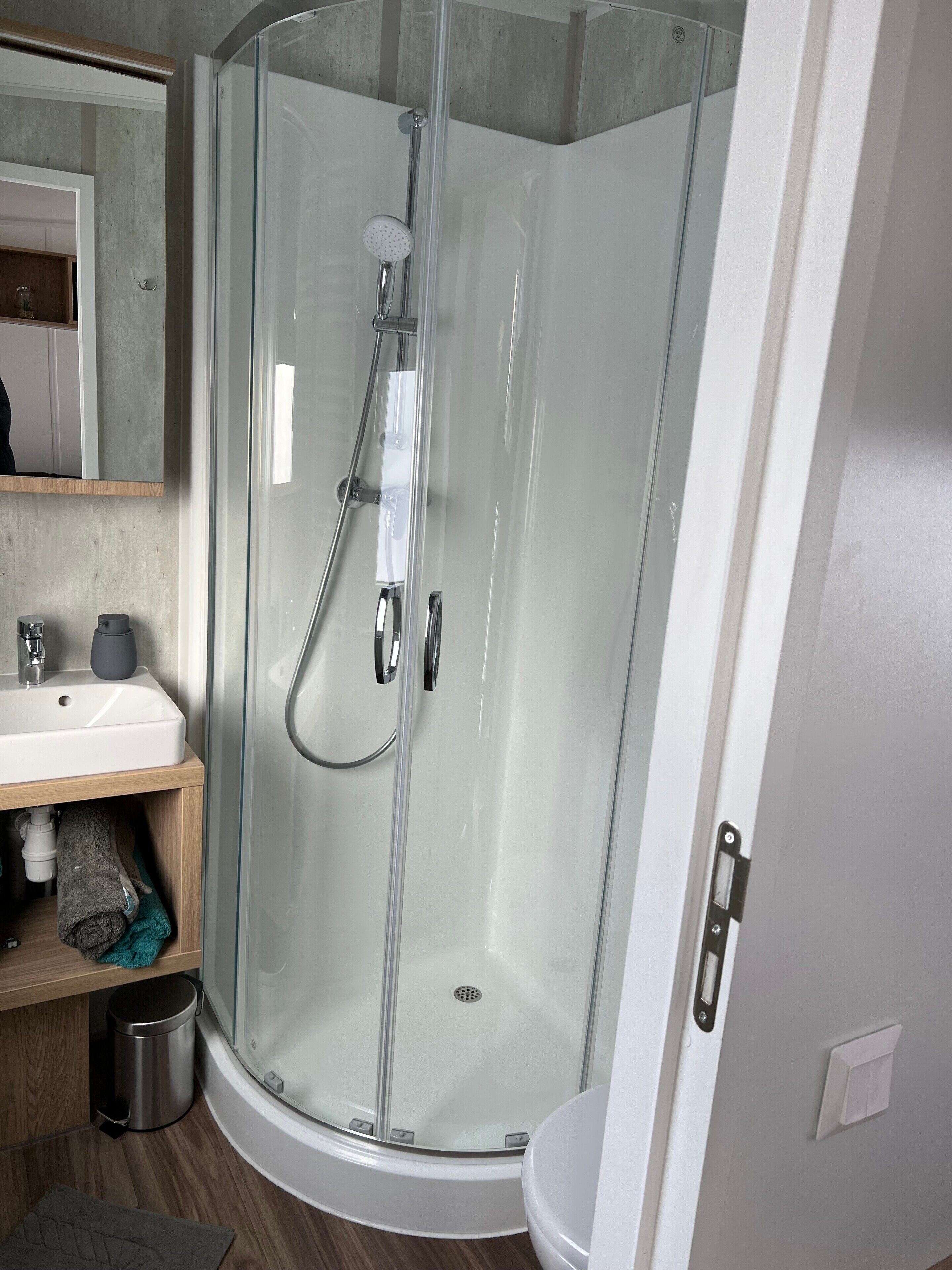 Un baño moderno con ducha envuelta en vidrio, un lavamanos y un inodoro.