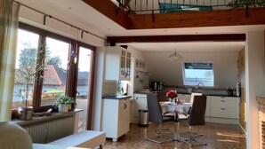 A kitchen with a dining area, wooden beams, and a view of the outside. - Apartment 'Maisonette Am See' with Lake View, Wi-Fi and Air Conditioning (Nonnenhorn)