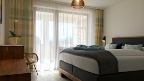 A bedroom with a bed, a desk, a chair, a potted plant, and a view through the window. - Apartment 'Maisonette Am See' with Lake View, Wi-Fi and Air Conditioning (Nonnenhorn)