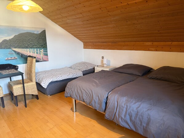 A bedroom with a bed, a desk, a chair, and a nightstand.