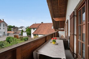 Un balcon avec une table, des chaises et un pot de fleurs.