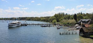 A lake with a dock, boats, and a building with a sloped roof.