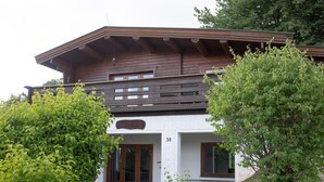 A two-story building with a wooden facade, a balcony, and a sign indicating it is a guesthouse. - Cozy Log Cabin in the Harz with Private Terrace & Garden (Bad Sachsa)