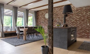 Una cocina moderna con pared de ladrillo, vigas de madera y zona de comedor con mesa y sillas.