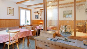 A cozy room with wooden beams, a dining table with chairs, a bench, and a large window with frosted glass. - Room '4 with WC and Shower' with Shared Terrace and Wi-Fi (Lenzkirch)