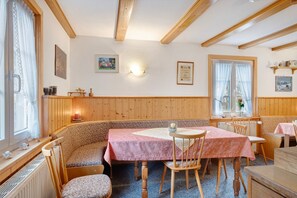 Ein gemütlicher Essbereich mit Holzbalken, einem Tisch mit rosa Tischdecke und einer Bank.