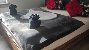 Un dormitorio con cama, almohadas, una mesita de noche y una ventana.