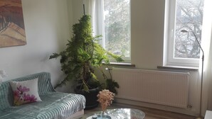 Una sala de estar con un sofá, una mesa de centro, una planta en maceta y un radiador.